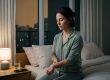 Woman using calming wrist acupressure at bedtime with phone set aside during smoke season — Artemis Wellness Clinic, Richmond BC